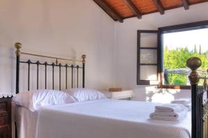 Villa Verde في Kounavádes: غرفة نوم بسرير وملاءات بيضاء ونافذة