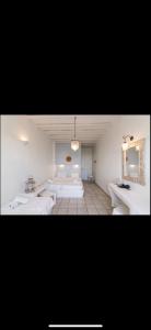 a large room with two beds and a mirror at Studios Eleni II in Tinos