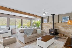 a living room with a couch and a fireplace at Secluded Waterfront House on Rainforest Acerage in Wisemans Ferry