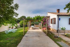 a garden with a pergola next to a house at Charming holiday house with beautiful garden and grill in Loborika