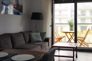 a living room with a couch and a table at Widok na Morze Apartament przy plaży Premium by STAYLY in Dziwnów