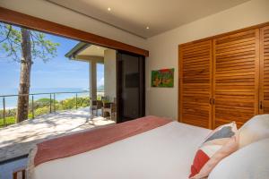 a bedroom with a large bed and a balcony at Luxe 4 Bdrm Villa with Epic OceanView & Infinity Pool in Dominicalito