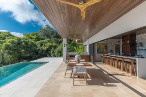 an outdoor kitchen and dining area with a pool and a house at RESOL Secluded Ocean-view luxury in the Jungle in Uvita