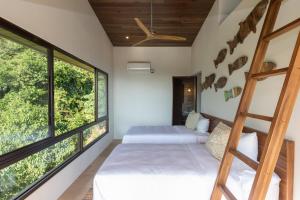 two beds in a room with large windows at RESOL Secluded Ocean-view luxury in the Jungle in Uvita