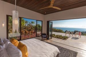 a bedroom with a large bed and large windows at RESOL Secluded Ocean-view luxury in the Jungle in Uvita