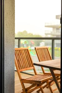 2 sillas de madera y una mesa en el balcón en Widok na Morze Apartament przy plaży Premium by STAYLY, en Dziwnów