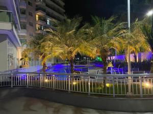 a resort with palm trees and a pool at night at Suíte & Flat Premium Rio Stay - Rio Centro in Rio de Janeiro