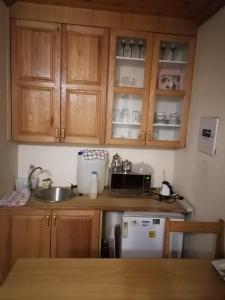 a kitchen with wooden cabinets and a sink and a microwave at Tjibelu's Nest Guest Home in Lobatse