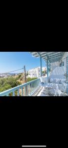 a balcony with white chairs and a blue railing at Studios Eleni II in Tinos
