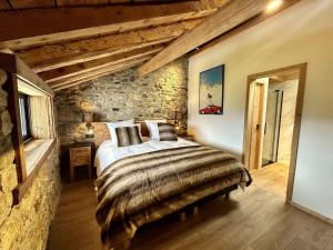 a bedroom with a large bed in a stone wall at Le Refuge Cal Chalon , chalet de luxe au cœur du village in Les Angles