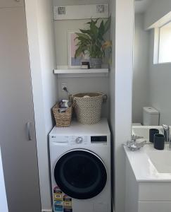 uma máquina de lavar roupa na casa de banho ao lado de um lavatório em Bealey Avenue Apartment, 2 Bedroom apartment, Central City em Christchurch