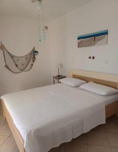 een slaapkamer met een wit bed en een hangmat aan de muur bij Dalmas apartmani in Vela Luka