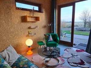 ein Wohnzimmer mit einem grünen Stuhl und einem Glastisch in der Unterkunft Silver Garden in Oosterend