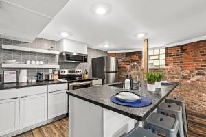 a kitchen with white cabinets and a brick wall at The Midtown Hideaway in Detroit