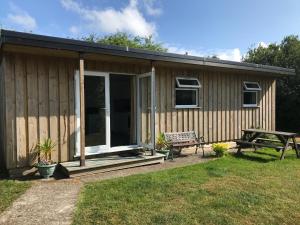 a wooden cabin with a picnic table and a bench at Kingfisher Glamping Cabin in Bodmin
