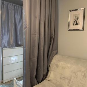 - une chambre avec un lit et un rideau à côté d'une commode dans l'établissement Studio climatisé avec piscine, à Saint-Raphaël