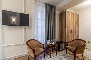 a living room with two chairs and a table and a tv at Oscar Hotel by AG Hotels Group in Almaty