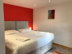 a bedroom with a bed with a red wall at Woodpecker Glamping Cabin in Bodmin