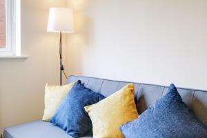 a blue couch with pillows sitting next to a lamp at Harry Potter, Warner Brothers Apartment - Watford Junction - Watford FC - Free Parking in Watford