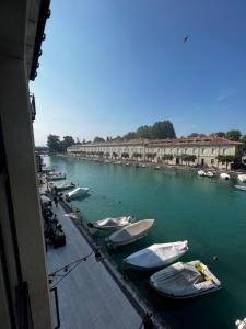 a group of boats are docked in a river at C House Rooms Lake in Peschiera del Garda