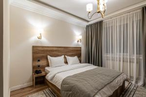 a bedroom with a bed and a chandelier at Oscar Hotel by AG Hotels Group in Almaty