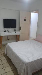 1 dormitorio con 1 cama y TV en un escritorio en SUITE e QUARTOS -1 SUITE COM BANHEIRO PRIVATIVO - 2 QUARTOS DUPLOS COM BANHEIRO COMPARTILHADO, en Recife