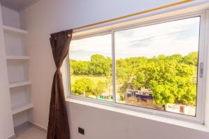 - une fenêtre dans une chambre avec vue sur les arbres dans l'établissement Hotel Dellhar Americano By Del Toro, à Doradal