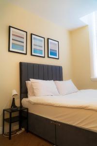 a bed in a bedroom with three pictures on the wall at Great offers on Long Stays!! LaLuNa Apartments in Gateshead