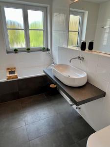 a white bathroom with a sink and a bath tub at UNiQE I Stilvolle 115qm I Terrasse I BBQ in Feldafing