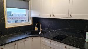 a kitchen with black marble counter tops and a window at Apartament plac Żołnierza Szczecin Polska in Szczecin