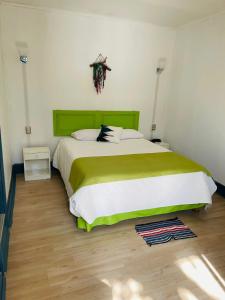 a bedroom with a large bed with a green headboard at ICCE HOTEL in Santiago