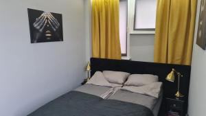 a bedroom with a bed and a window with yellow curtains at Apartament plac Żołnierza Szczecin Polska in Szczecin