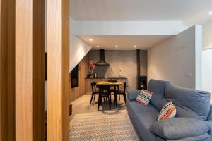 a living room with a blue couch and a kitchen at Maria Veiga Guest House in Viana do Castelo