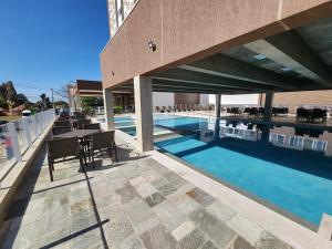 a swimming pool with tables and chairs next to a building at Spazzio diRoma - Apartamentos JN in Caldas Novas