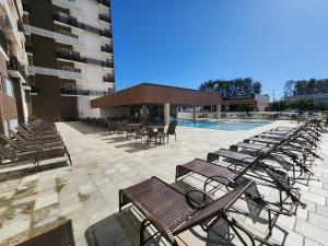 a group of chairs and tables and a swimming pool at Spazzio diRoma - Apartamentos JN in Caldas Novas