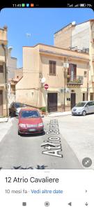 un coche rojo estacionado en un estacionamiento al lado de un edificio en La Casetta Nell' Atrio Cavalieri, en Bagheria