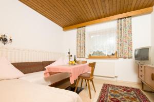 a bedroom with a table and a bed and a tv at Gästehaus Helga in Scharnitz