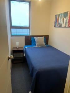 Un dormitorio con una cama azul y una ventana en Departamento full equipamiento, en San Pedro de la Paz