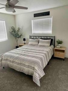 a bedroom with a bed with a striped comforter and two tables at Cozy Adventure Casita in St. George
