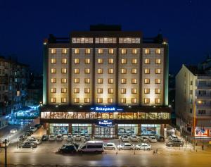 ein großes Gebäude mit Autos auf einem Parkplatz in der Unterkunft Ozkaymak Konya Hotel in Konya
