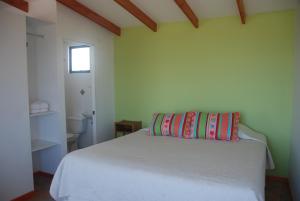 a bedroom with a white bed with a pillow on it at Cabanas Las Hualas in Punta de Choros