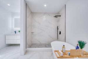 een witte badkamer met een bad en een douche bij Red Door Oasis in Milton