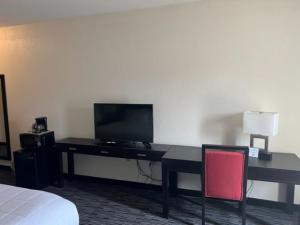 a hotel room with a desk with a television and a bed at American Inn and Suites Houghton Lake in Houghton Lake