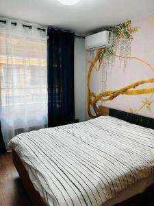 - une chambre avec un lit et un arbre sur le mur dans l'établissement бутиков апартамент Деси, à Pomorie