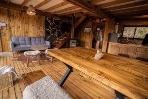 salon z kanapą i drewnianym stołem w obiekcie Cabañas Borde Rio Las Trancas w mieście Nevados de Chillan