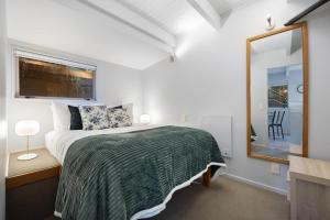 a bedroom with a bed and a mirror and a window at Bluebird Stay in Queenstown