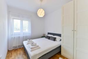 a white bedroom with a bed and a window at LUXURY MARIJANA APARTMENT in Privlaka