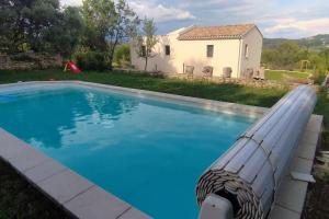 una piscina frente a una casa con una casa blanca en Gîte Aux Bons Voisins en Gordes