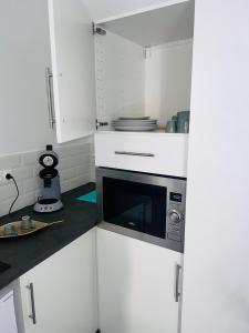 La cuisine est équipée de placards blancs et d'un four micro-ondes. dans l'établissement SPA JUNGLE, à Le Mesnil-Saint-Denis