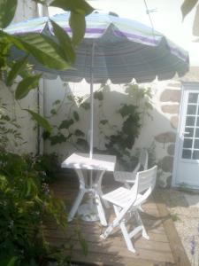 - une table et deux chaises sous un parasol sur la terrasse dans l'établissement Idéal pour les amoureux de la pierre intérieure, à Palluau